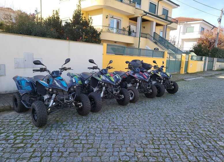 A row of quad bikes parked on a cobblestone street. 5