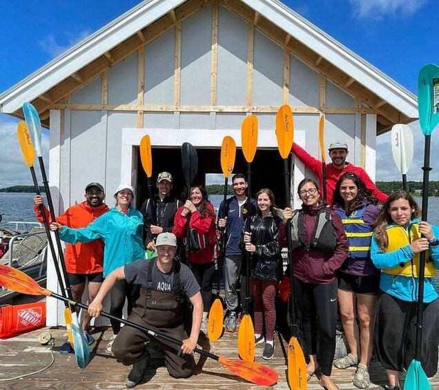 A group of people with kayaks in front of a building with a wooden roof. 3