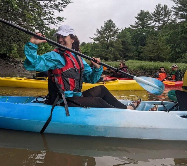 A person kayaking on a river surrounded by greenery. 4