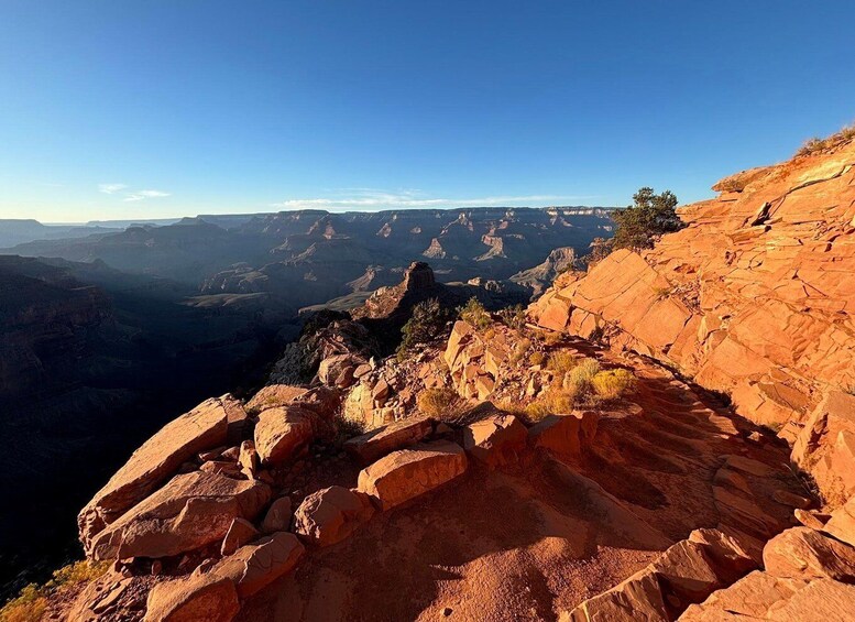 A canyon with layered rock formations and a clear blue sky. 2