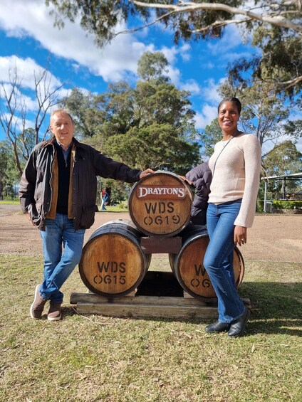 Two people standing next to wooden barrels with inscriptions. 3