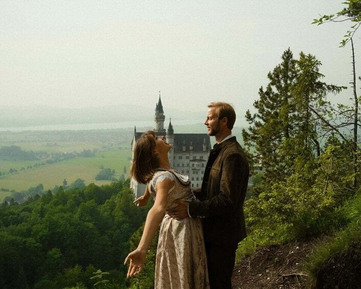 Ett par står på en kulle med utsikt över ett slott och ett landskap. 2