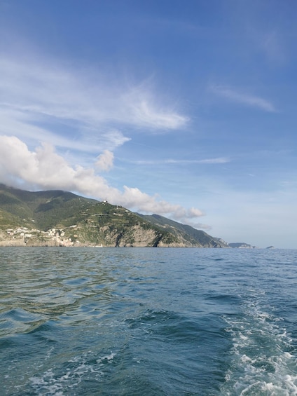 A coastal landscape with a clear sky, calm sea, and a village on a hillside. 4