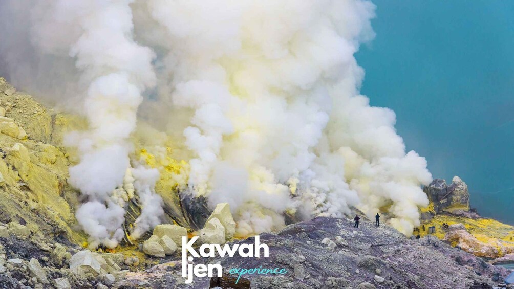 A volcanic eruption with steam and smoke, rocky terrain, and a clear blue sky. 5