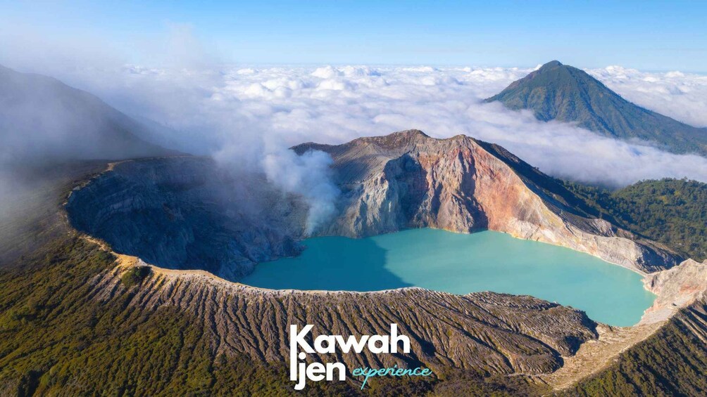 A volcanic crater with a turquoise lake surrounded by forested hills and a mountain in the background. 3