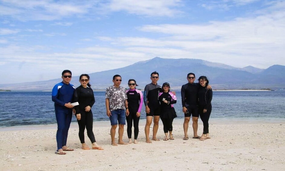A group of people standing on a beach with a mountain in the background. 4