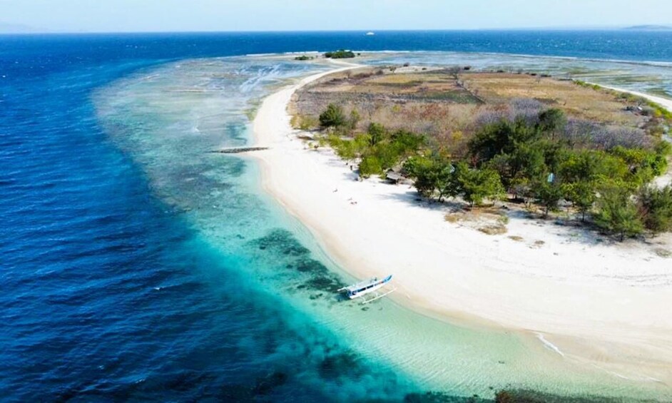 A beach with clear turquoise waters, a sandy shore, and a boat anchored near the water's edge. 2