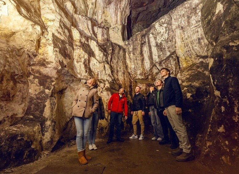 A group of people standing in a cave with rocky walls. 1
