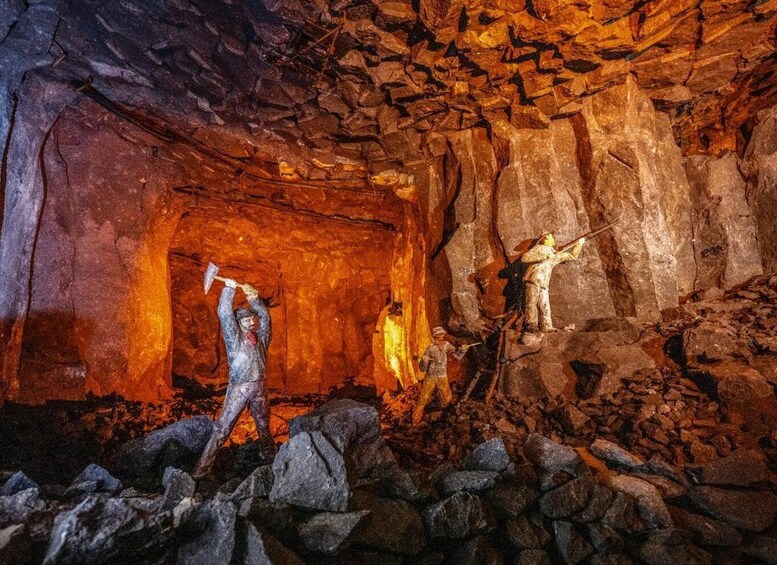 A cave with two miners working inside, surrounded by rocky walls and a warm light source. 3