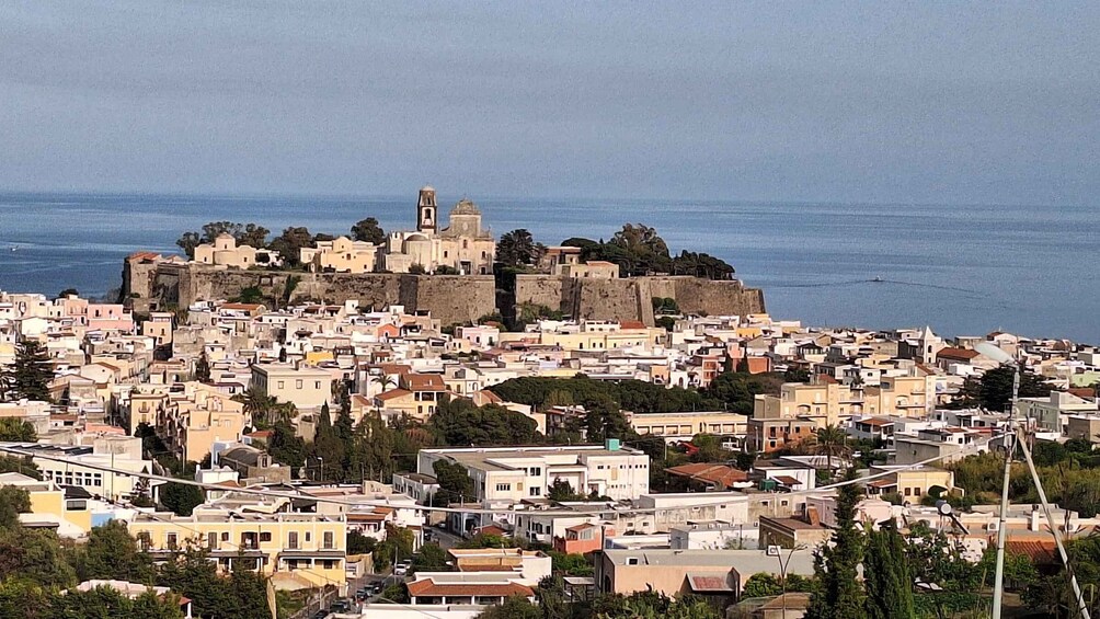 A coastal town with historic architecture and a prominent fortress on a hill. 1