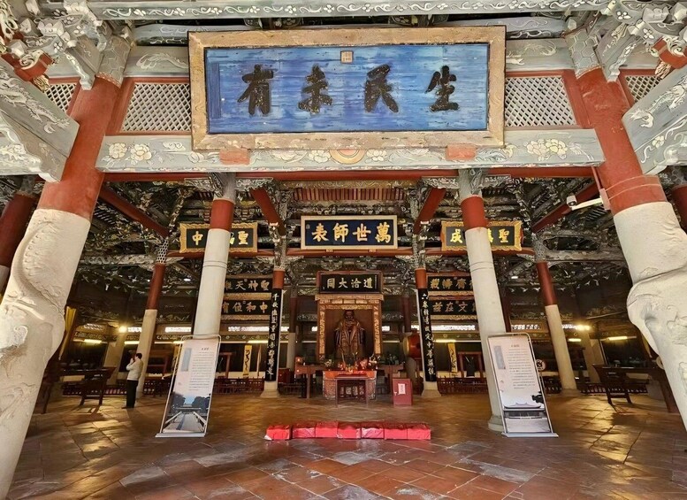 A traditional Chinese architectural structure with ornate carvings and a central blue plaque. 1