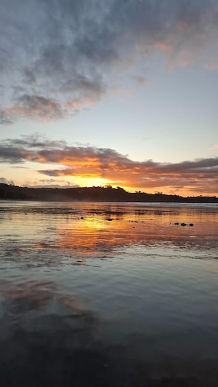 A sunset over a calm body of water with reflections of the sky. 1