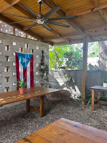 A wooden patio with a ceiling fan, a table, and a flag. 3