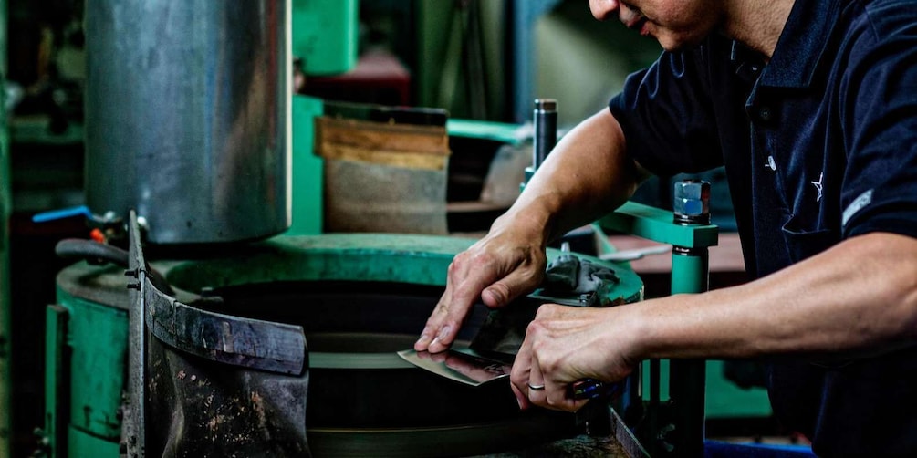 A person working with a metal object on a lathe machine. 1