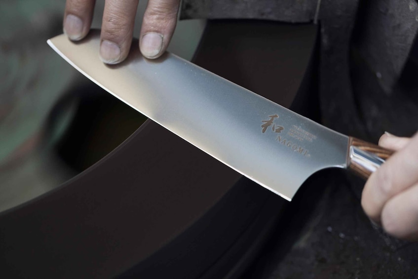 A person holding a large knife with a wooden handle. 3