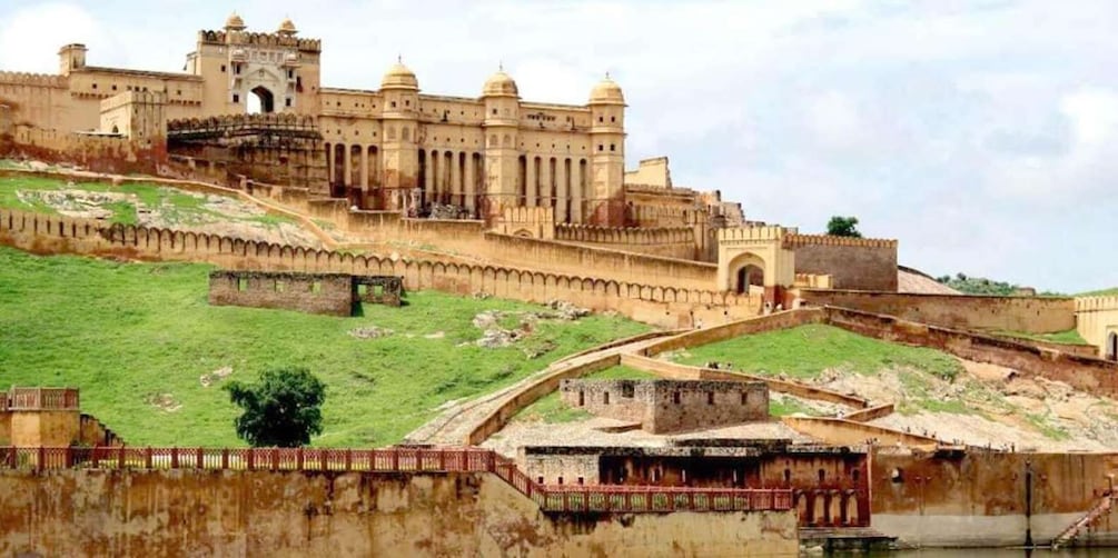 A historic fort with a large central building, a surrounding wall, and a river in the foreground. 4