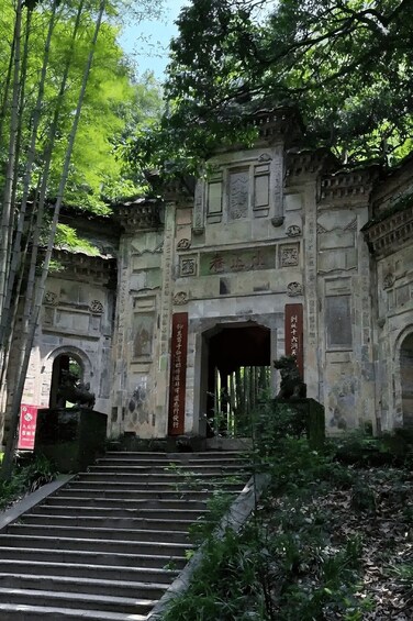 A traditional stone gate with inscriptions, surrounded by lush greenery and bamboo. 3