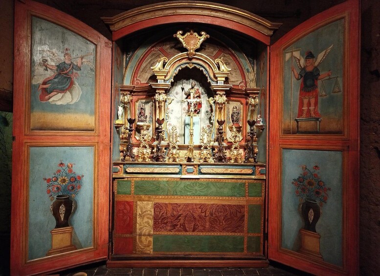 An ornate religious altar with intricate carvings and statues, surrounded by framed paintings. 2