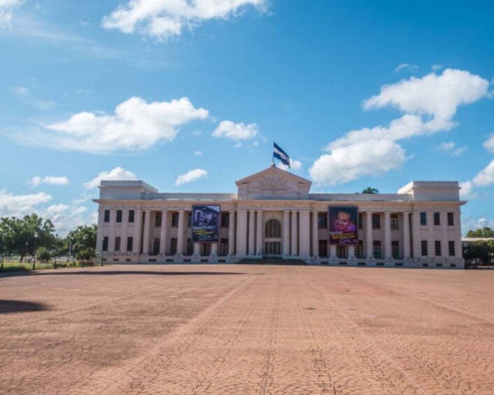 A large building with a flag on top, columns, and banners. 2