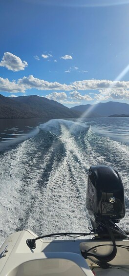 A boat moving through a lake with mountains in the background. 2