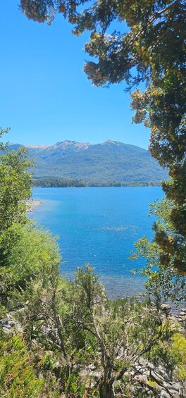 A clear blue lake surrounded by mountains and dense green foliage. 3