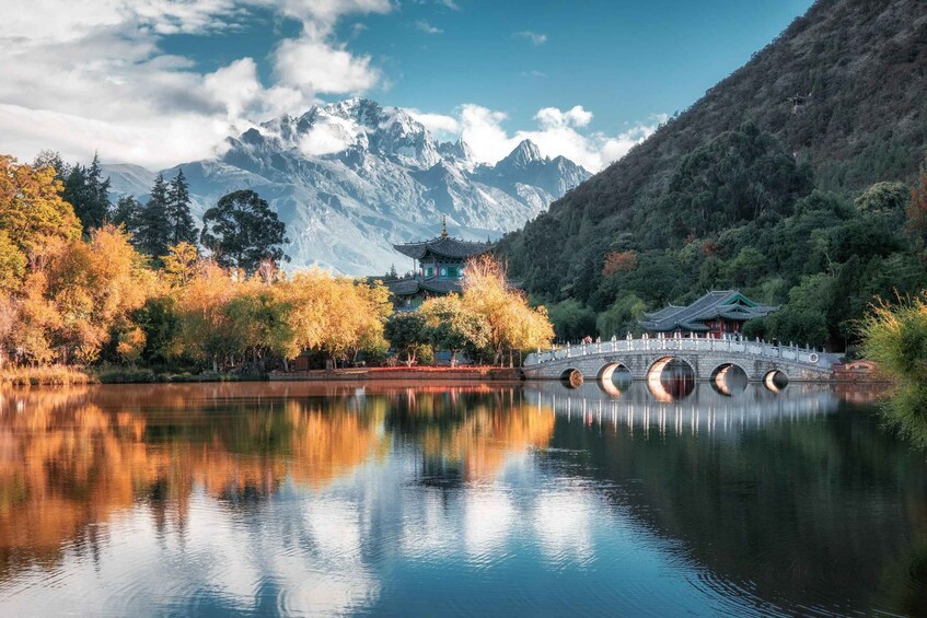 A serene lake with a traditional bridge, a pagoda, and mountains in the background. 5