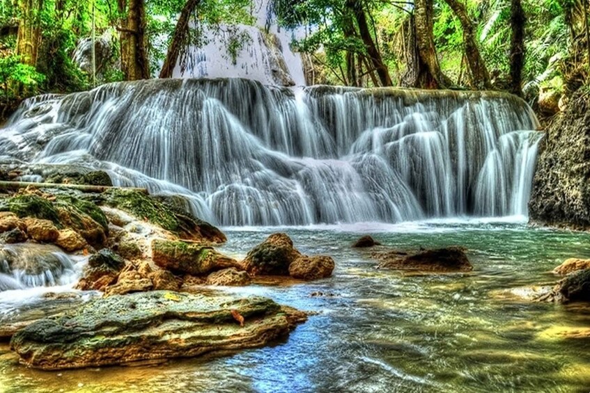 A waterfall cascading over rocks in a forested area. 1