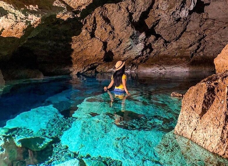A person meditating in a clear blue cave with rocky walls. 4