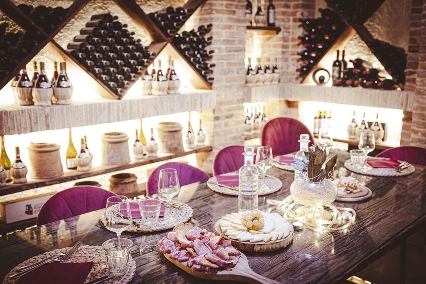 A restaurant interior with a long wooden table set for a meal, surrounded by wine racks and shelves. 5