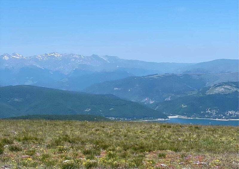 A mountainous landscape with a clear sky, a lake, and a distant town. 3