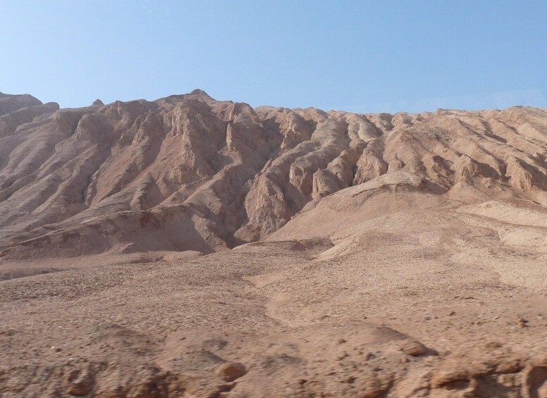 A desert landscape with rugged, eroded hills and a clear sky. 4