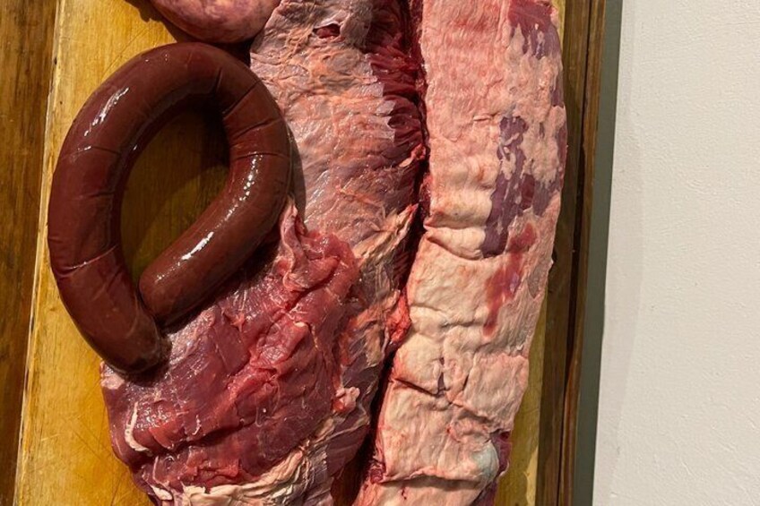 A raw meat slab with a sausage on a wooden surface. 3