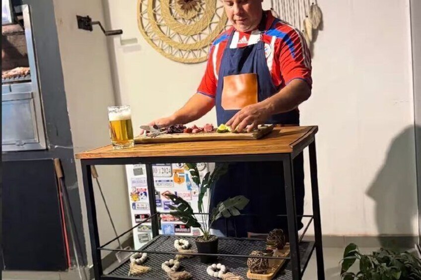 A person preparing food on a table with a beer glass and a plant. 1