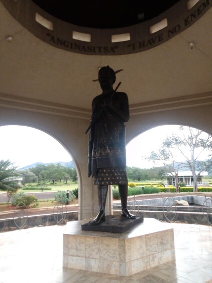 A statue of a person in traditional attire under a circular structure with inscriptions. 3