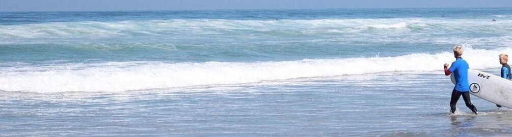 A person walking on the beach with a surfboard. 1