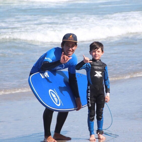 Two people on a beach holding a surfboard. 3