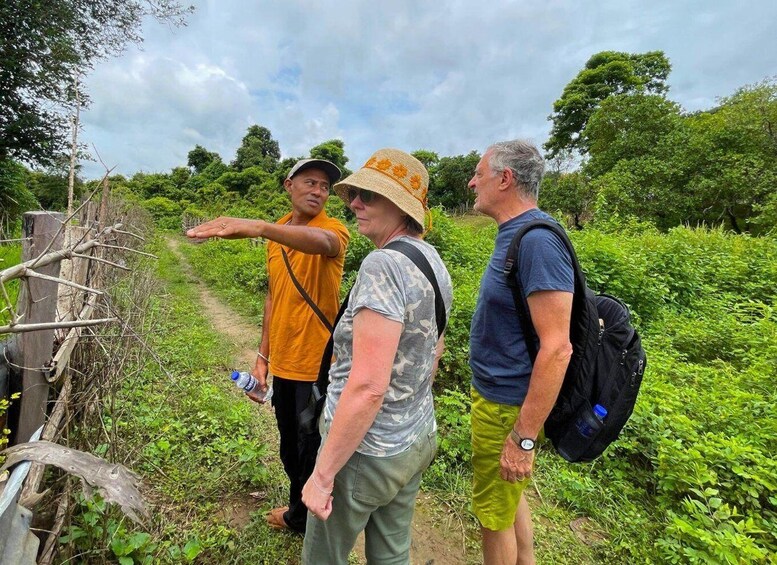 A group of people standing on a dirt path surrounded by greenery. 1