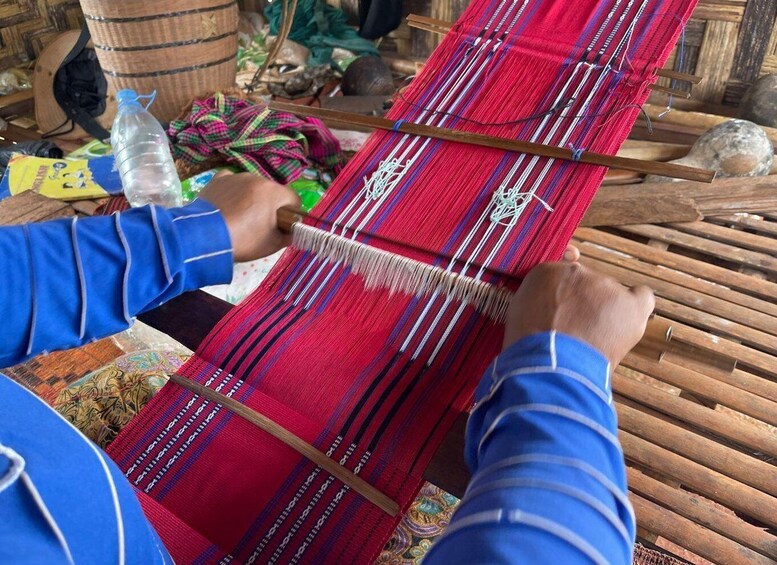 A person weaving on a loom with red and blue threads. 4