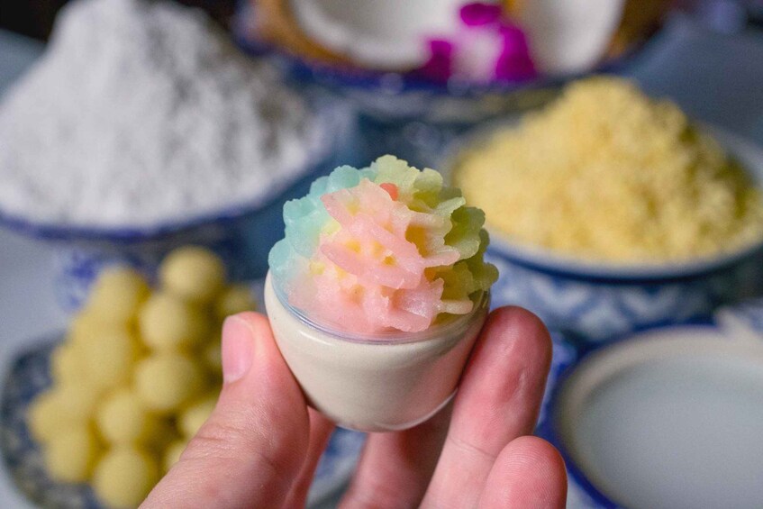 A hand holding a small cup with colorful ice cream. 5