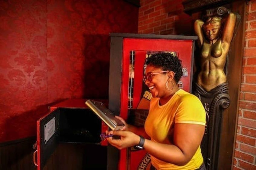 A person holding a book in front of a red door with a statue of a woman. 2