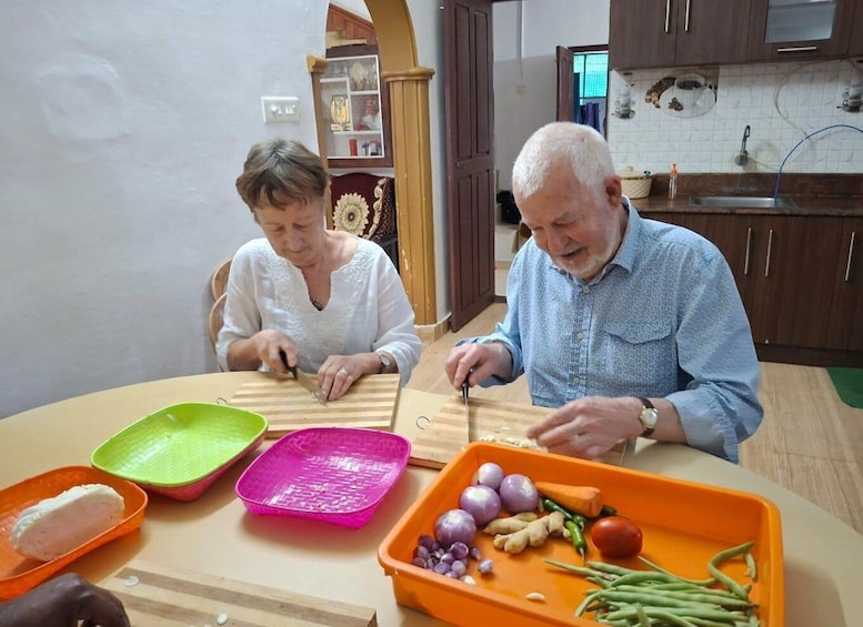 Two people cutting vegetables at a kitchen table. 4