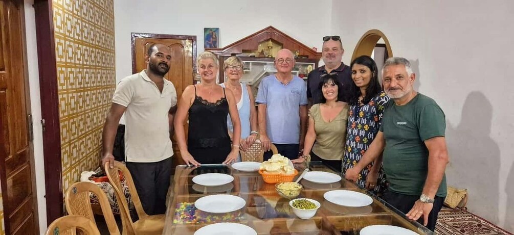 A group of people standing around a dining table with plates and food. 2
