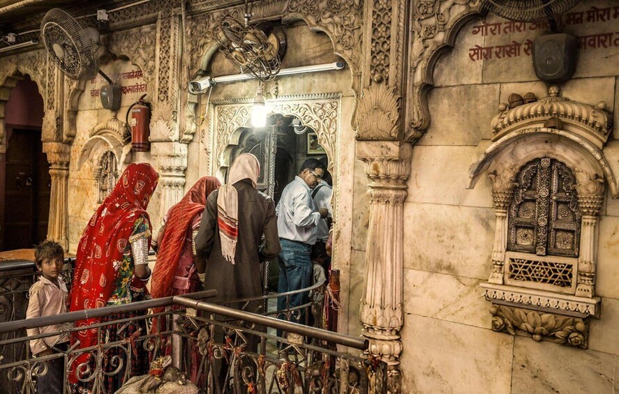 A group of people at a temple entrance with ornate carvings and a metal railing. 4