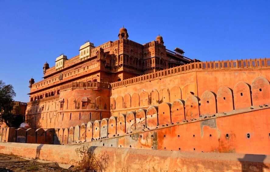A large, historic building with red sandstone walls and multiple domes. 1