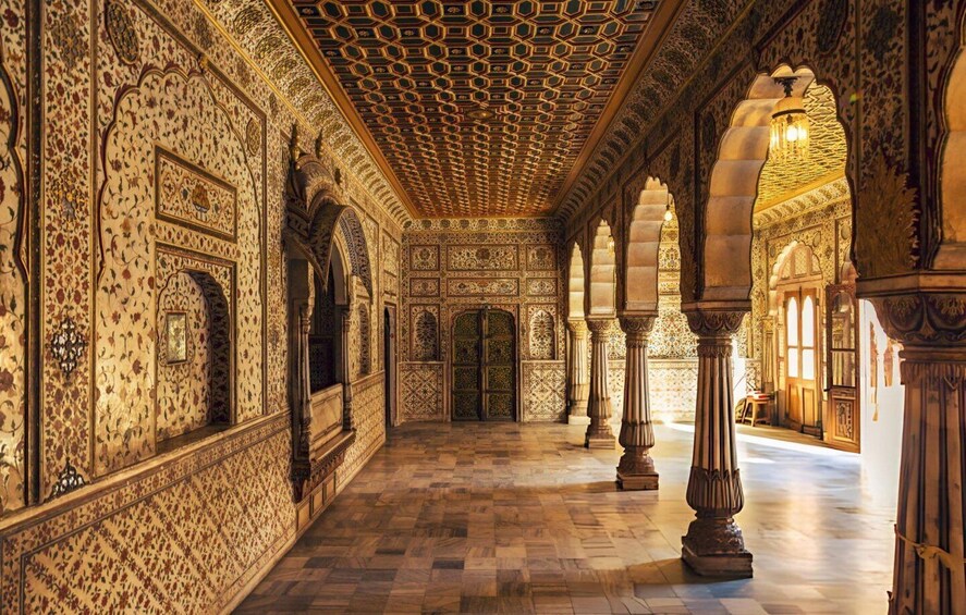 An ornate hallway with intricate tile work, arches, and columns. 2
