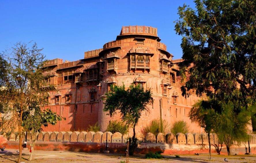 A historic building with intricate architecture, surrounded by trees and a clear sky. 5