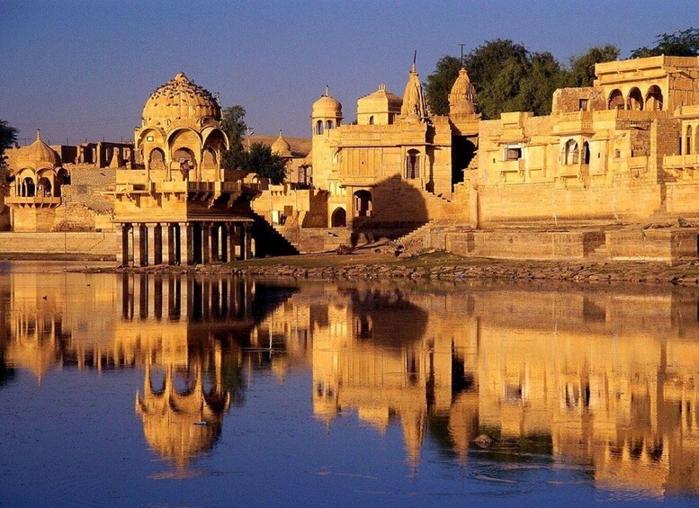 A historic architectural complex with domed structures and arched gateways, reflecting in a calm body of water. 4