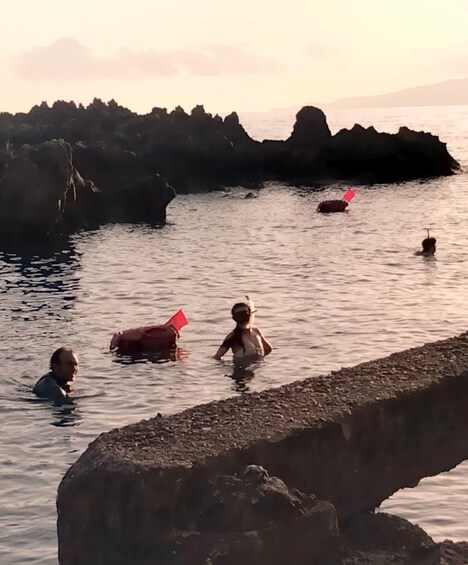 A rocky shoreline with people swimming in the water. 3