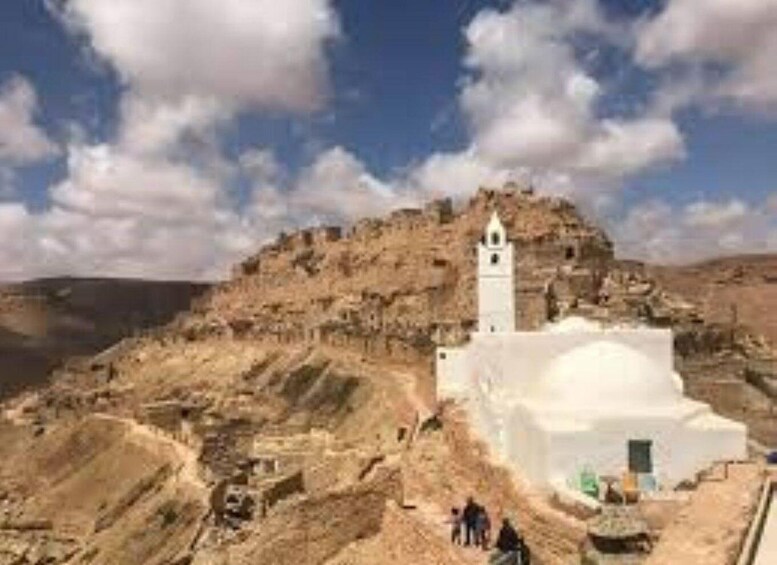 A white building with a bell tower on a rocky hill. 4