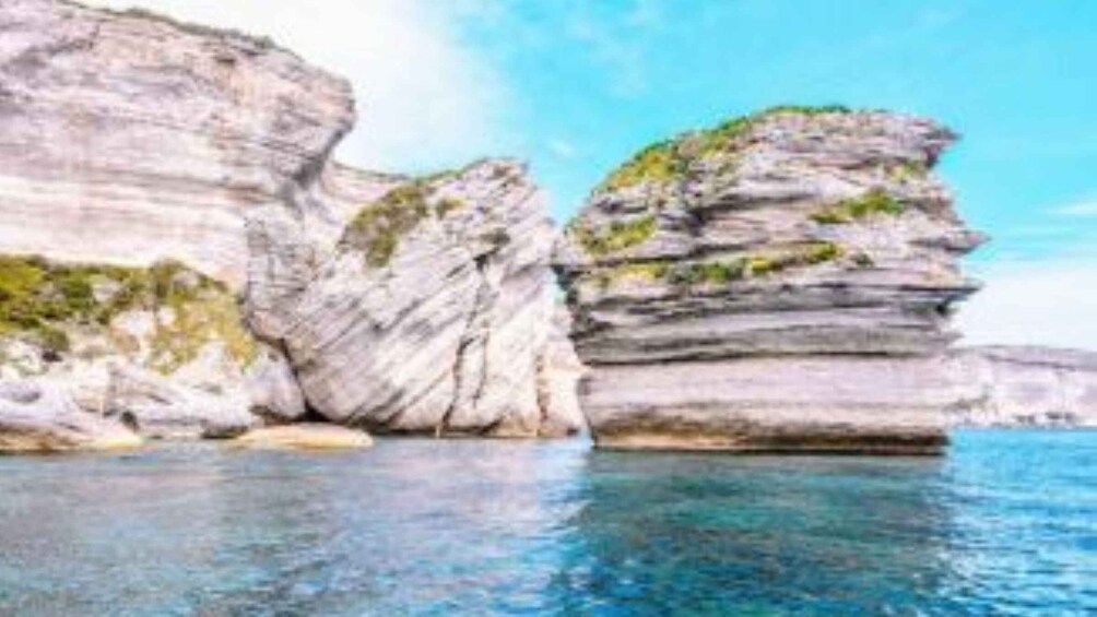 A coastal landscape with layered rock formations and clear blue water. 1